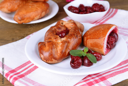 Foto Fresh baked pasties with cherry on plate on table close-up