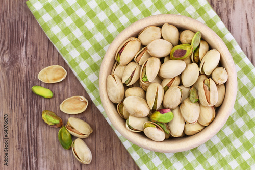 Obraz na płótnie Pistachio nuts in wooden bowl on checkered cloth w salonie