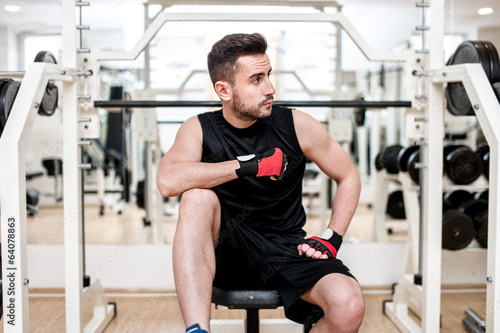 Man working out at gym, resting at bench press Man working out at gym, resting at bench press