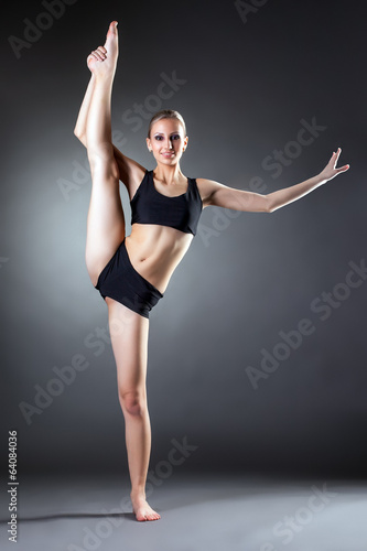 Fototapeta Naklejka Na Ścianę i Meble -  Smiling young woman posing on vertical splits