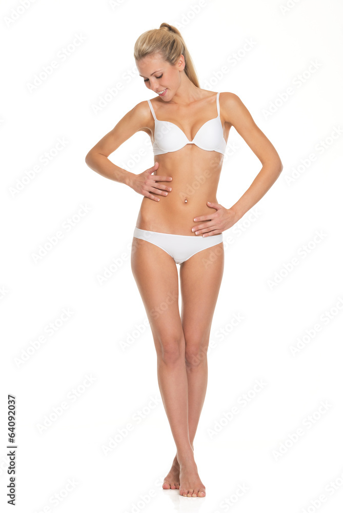 Full length portrait of young woman in lingerie checking body Full length portrait of young woman in lingerie checking body