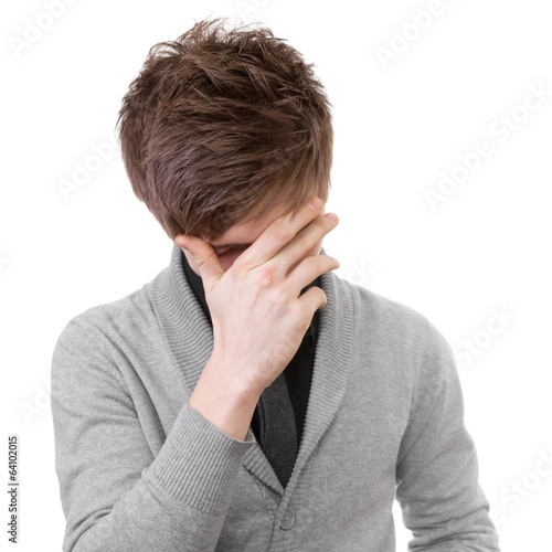 Sad young man covered his face with his hand. Isolation on white