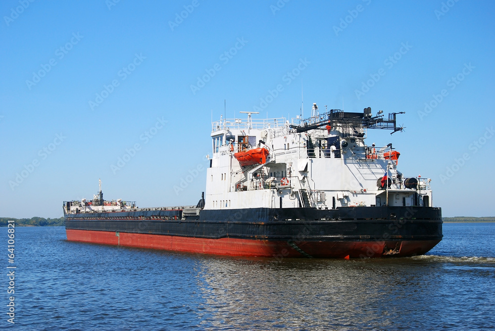 Industrial ship sails on blue water.