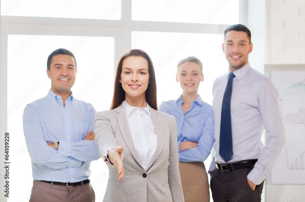 smiling businesswoman in office with team on back smiling businesswoman in office with team on back