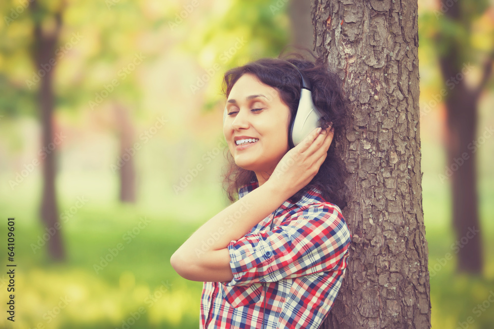 Indian girl with headphones in the park.
