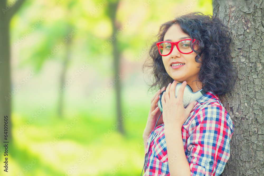 Indian girl with headphones in the park. Indian girl with headphones in the park.