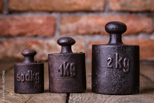 Obraz na płótnie Vintage iron weights in front of an old brick wall. w salonie