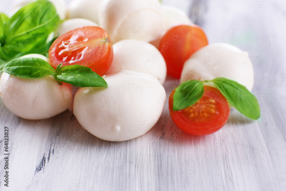 Tasty mozzarella cheese with basil and tomatoes, on wooden Tasty mozzarella cheese with basil and tomatoes, on wooden
