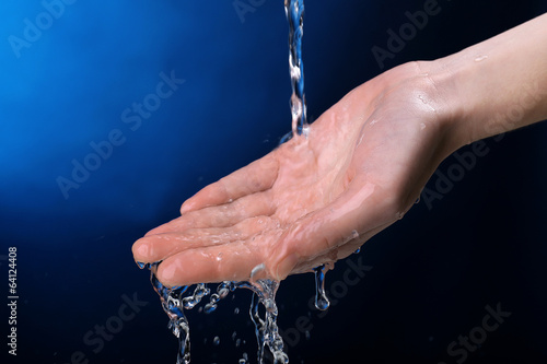 Human hand with water splashing on them on dark blue background