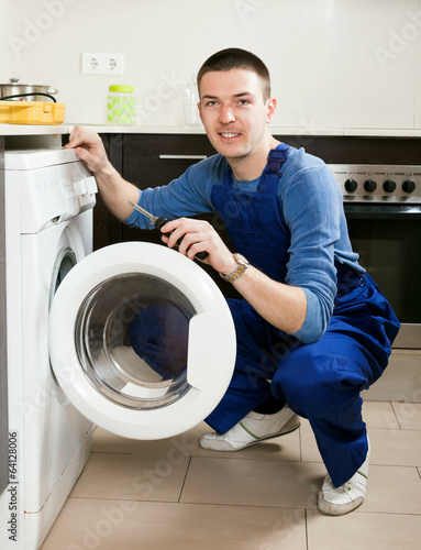 Repairman repairing washing machine at home