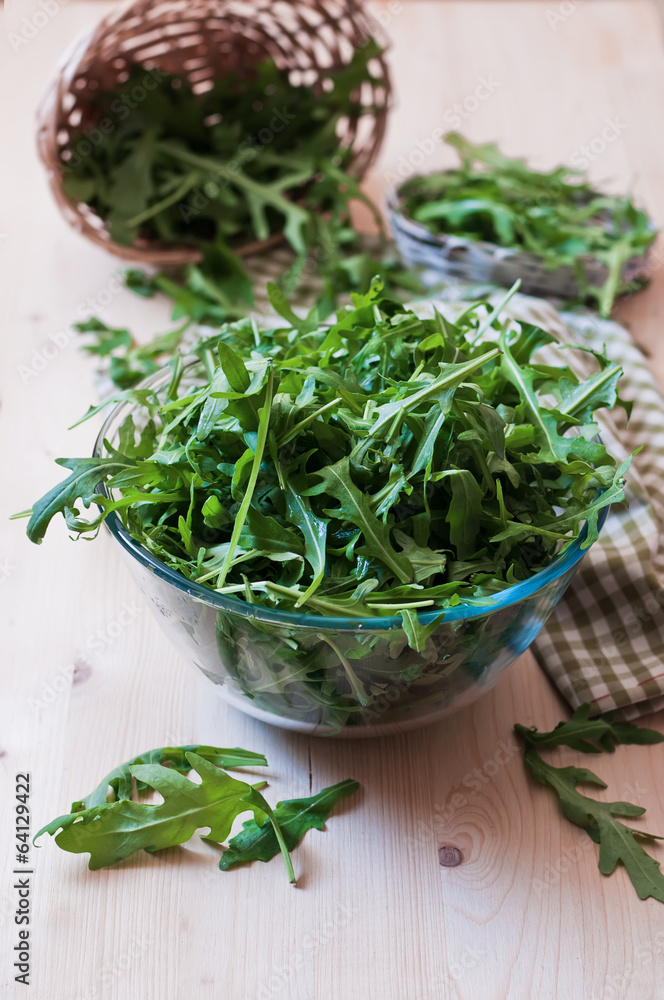 Fresh arugula in a glass plate on the wood  table
