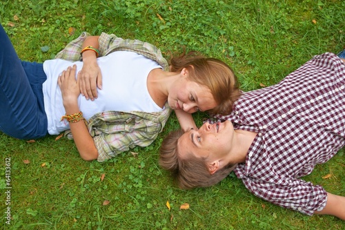 Boy and girl, teens lying on the grass, boy has braces