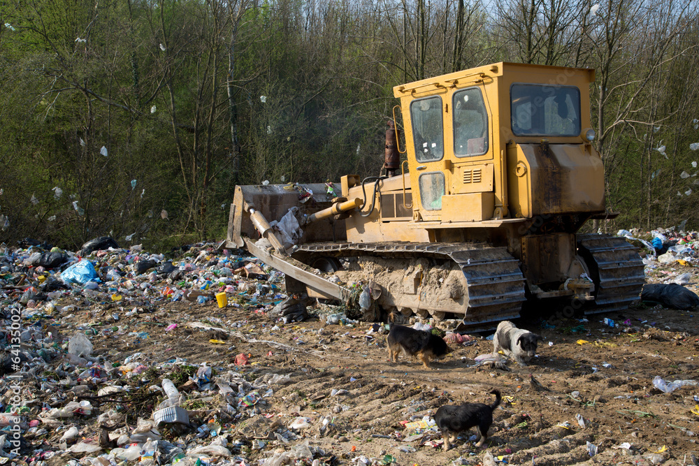 Fototapeta premium The old bulldozer moving garbage in a landfill