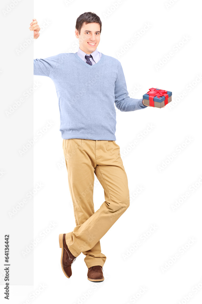 Man holding a present next to a blank panel Man holding a present next to a blank panel