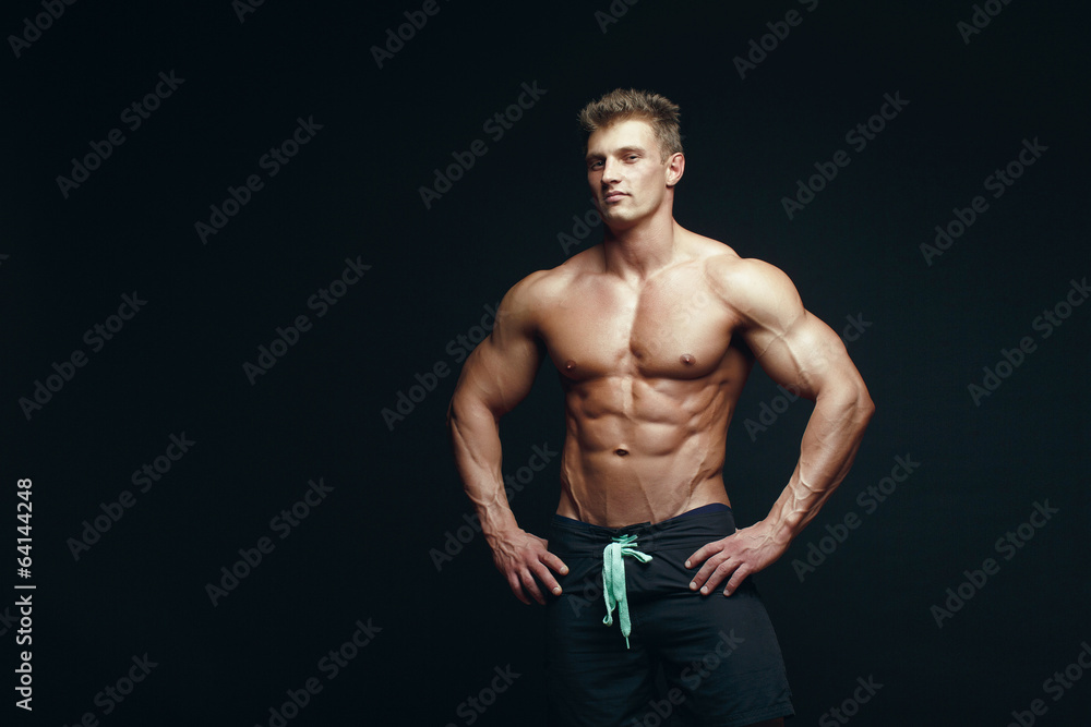 Fototapeta premium handsome muscular bodybuilder posing over black background.