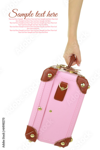 Hand holding a pink travel suitcase isolated on white