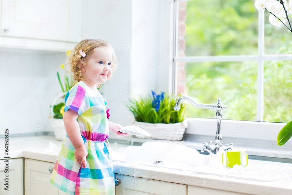 Cute curly toddler next sink in white kitchen Cute curly toddler next sink in white kitchen