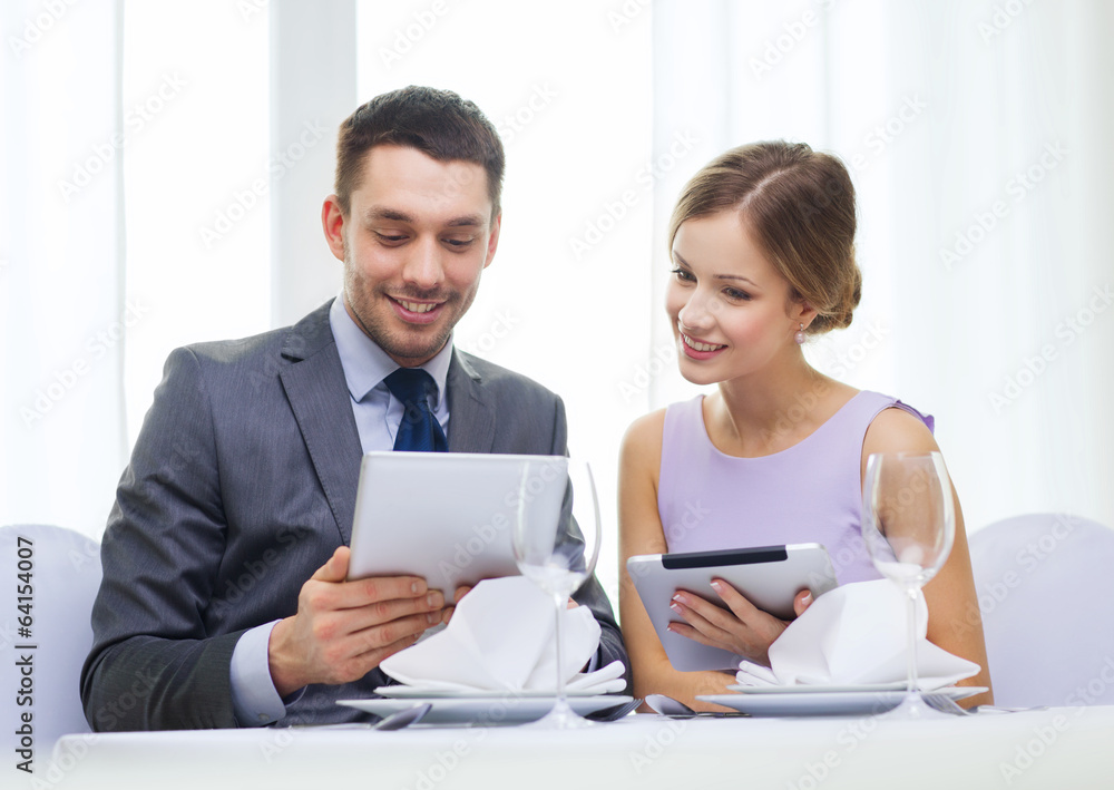 couple with menus on tablet pc at restaurant couple with menus on tablet pc at restaurant