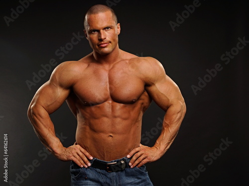 Handsome muscular man poses on gray background