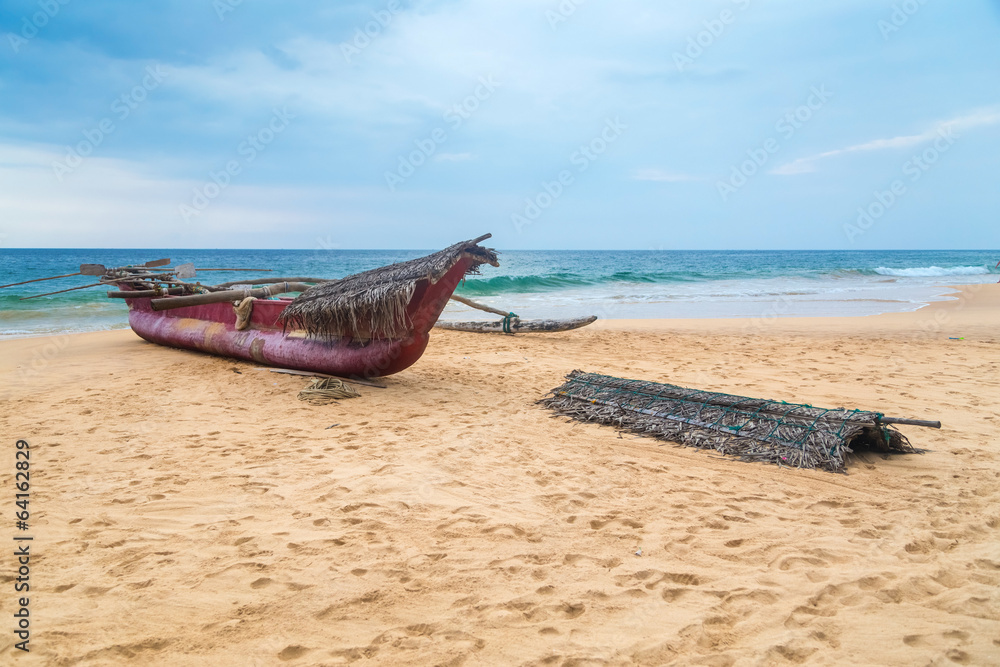 Traditional Sri Lankan fishing boat on empty sandy beach.