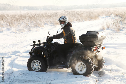 man driving a quad bike in the winter field