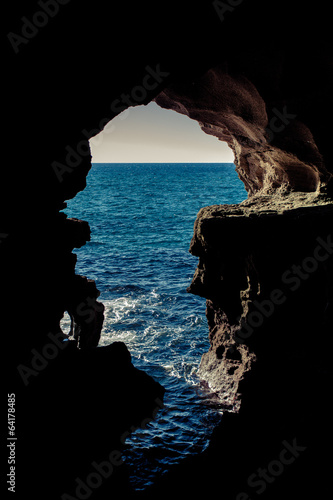View of the Atlantic ocean through a large hole in the cave