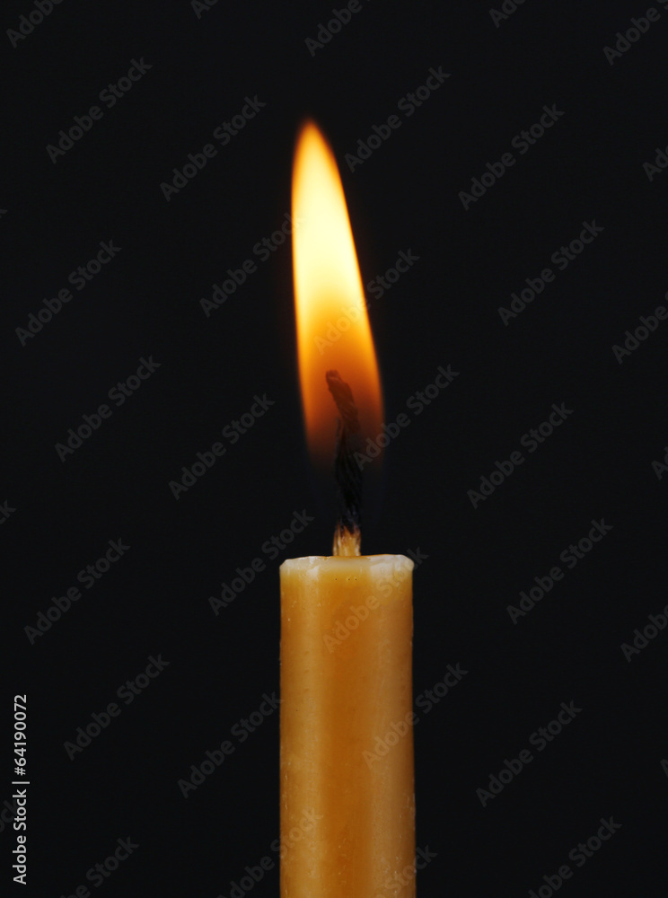 Burning candle on black background