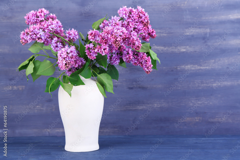 Beautiful lilac flowers in vase, on color wooden background Beautiful lilac flowers in vase, on color wooden background