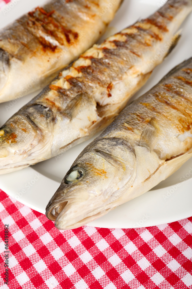 Delicious grilled fish on plate on table close-up Delicious grilled fish on plate on table close-up