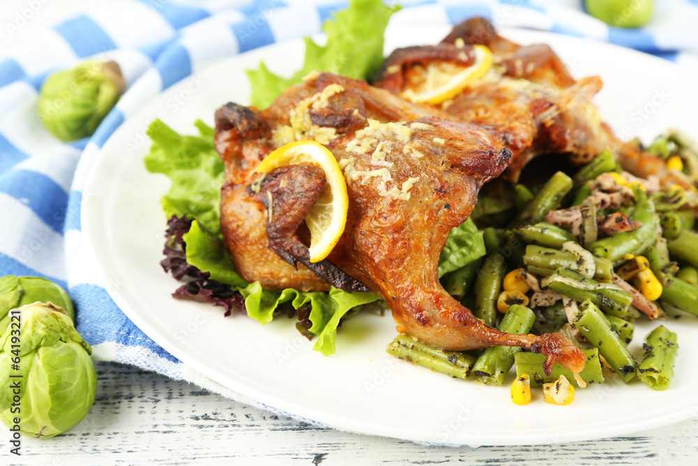 Roasted quails with vegetables on plate, on wooden background Roasted quails with vegetables on plate, on wooden background