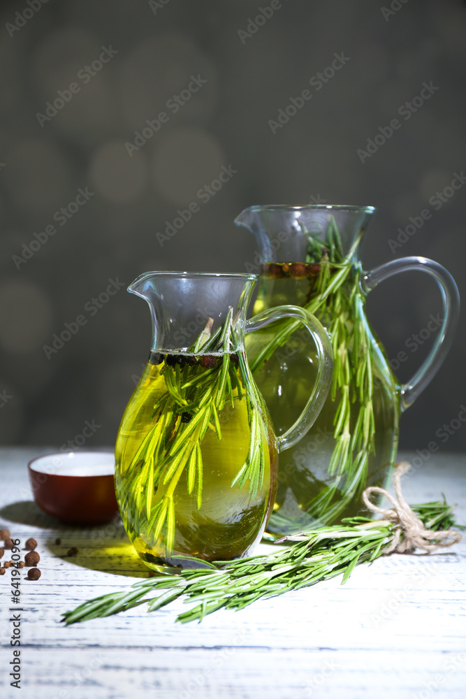 Essential Oil with rosemary in glass jug, on dark background Essential Oil with rosemary in glass jug, on dark background
