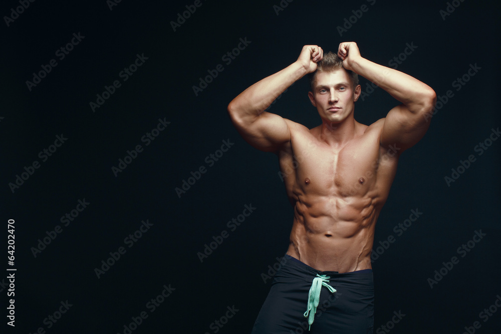 handsome muscular bodybuilder posing over black baсkgroung