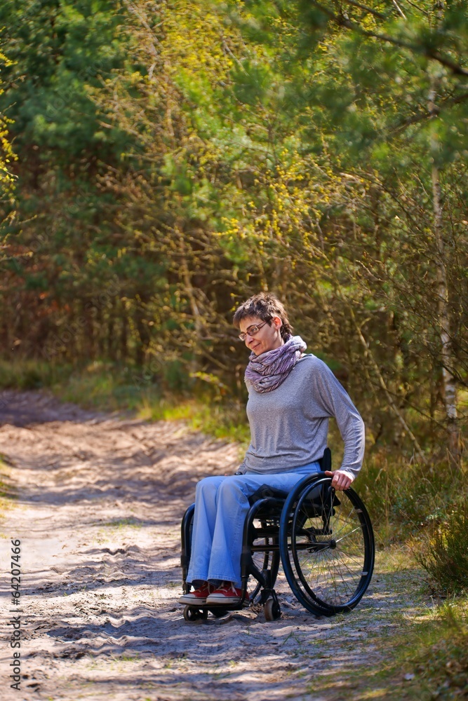 Disabled woman riding a wheelchair in the woods