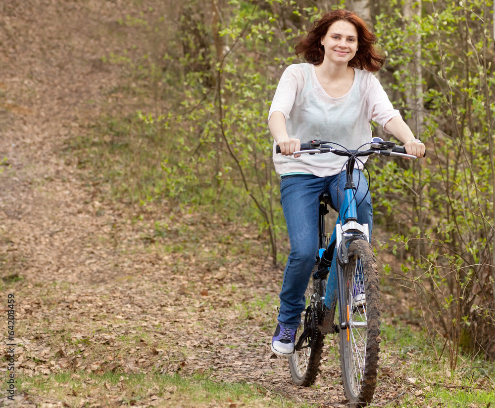 Naklejka premium beautiful young woman with bicycle in spring forest