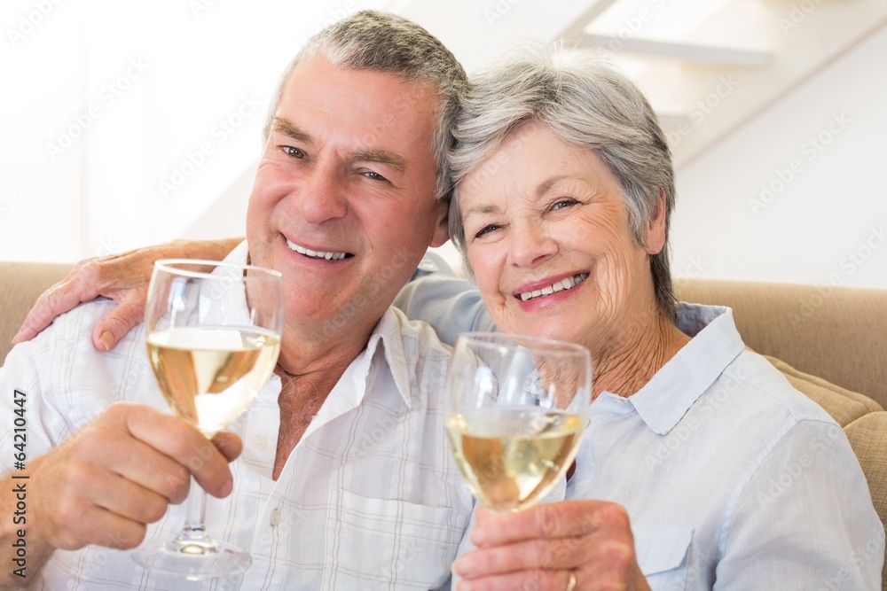Senior couple sitting on couch having white wine Senior couple sitting on couch having white wine