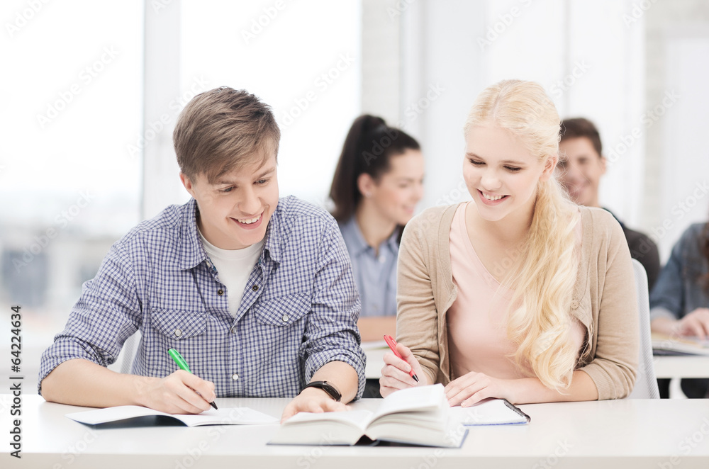 two teenagers with notebooks and book at school two teenagers with notebooks and book at school