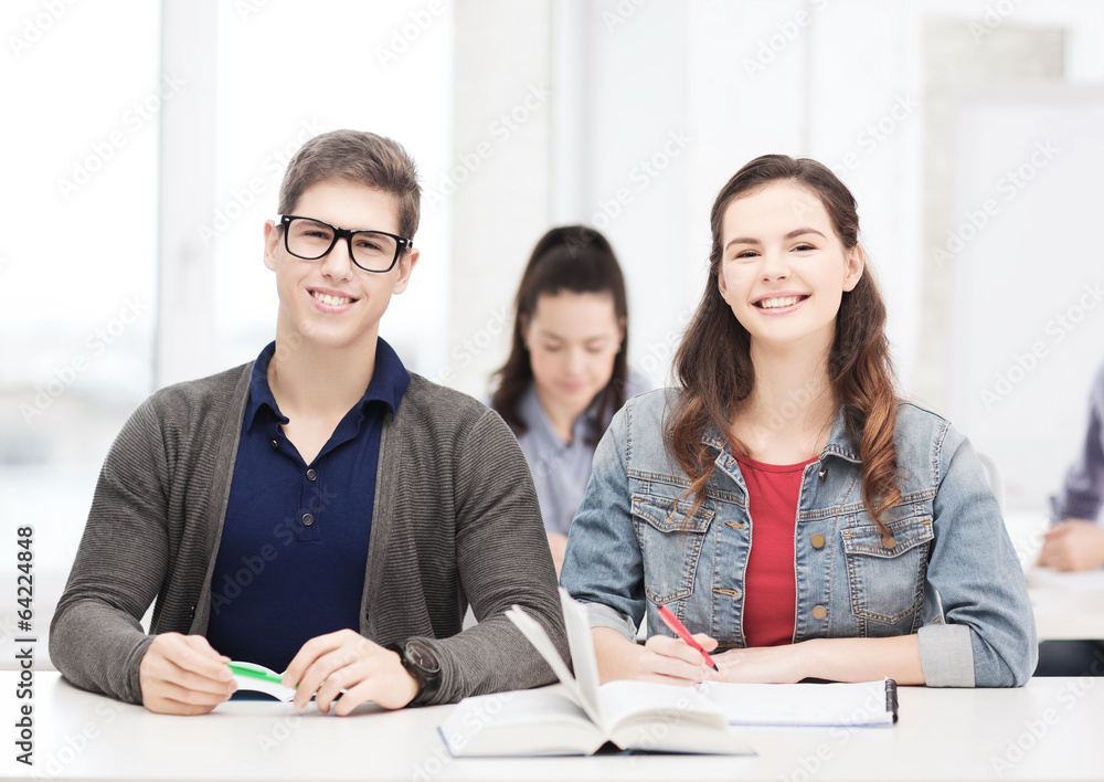 two teenagers with notebooks and book at school two teenagers with notebooks and book at school