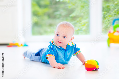 Little baby boy playing with a colorful ball and toy car
