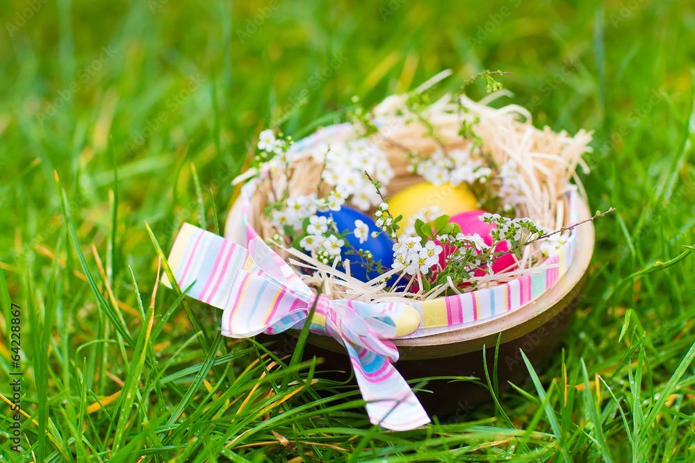 Basket with Easter flowers and colorful eggs on wet after rain Basket with Easter flowers and colorful eggs on wet after rain