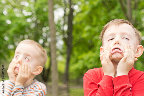 Fotografie Two young boys pulling funny faces