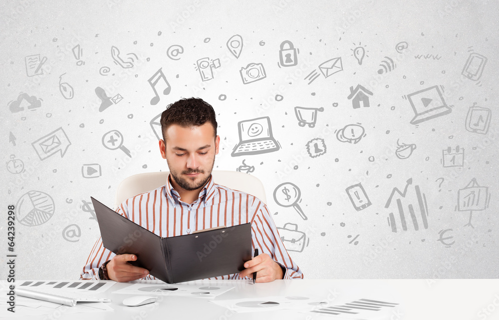 Business man sitting at table with hand drawn media icons Business man sitting at table with hand drawn media icons