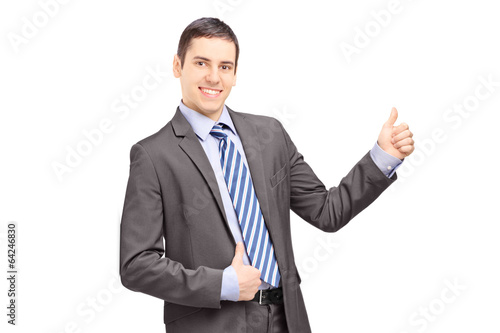Businessman leaning against wall and giving thumb up