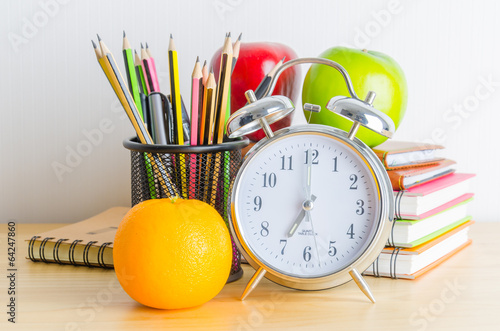 Back to school , note book , clock , pencil , apple on wood tabl