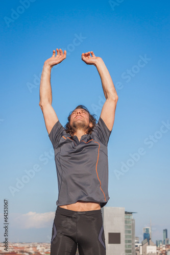 Long haired athlete stretching against blue sky