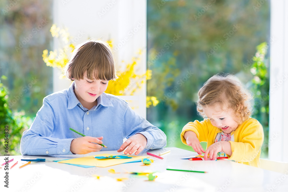 Fototapeta premium Two kids in sunny white dining room big garden view window