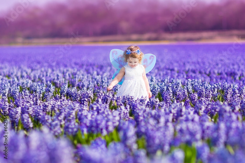 Cute toddler girl in fairy costume in a flower field