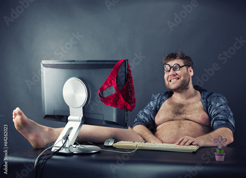Man sitting at desk looking on computer screen photo