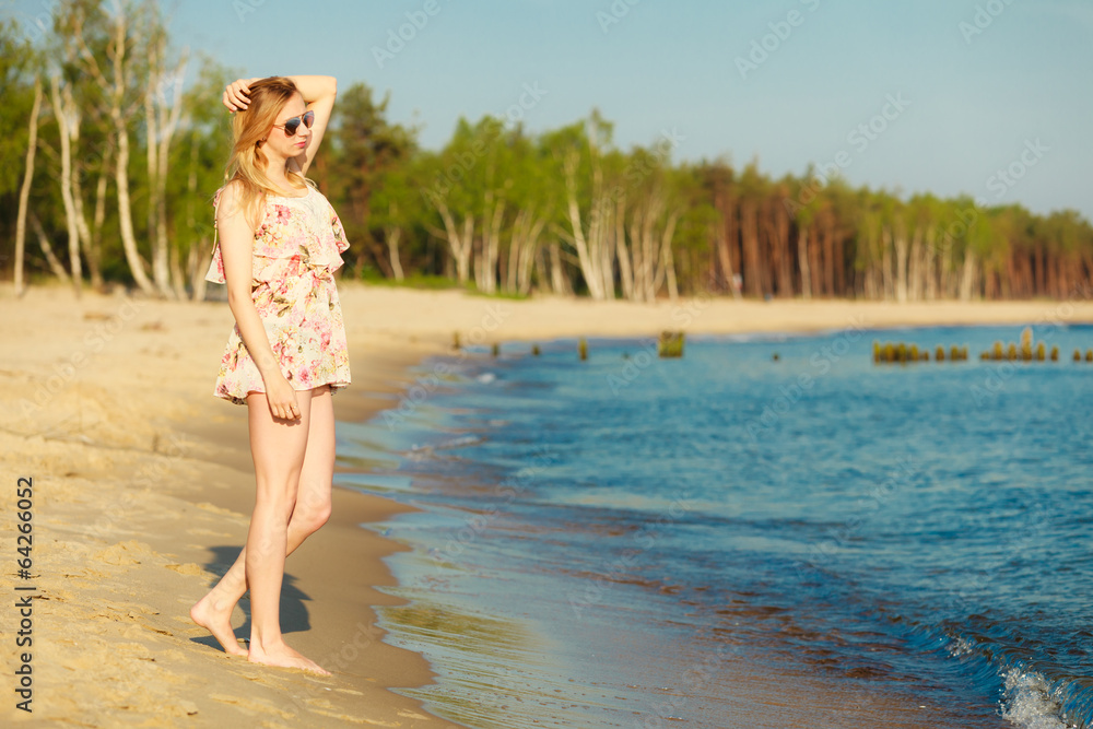 Fototapeta premium Summer vacation. Girl standing alone on the beach.