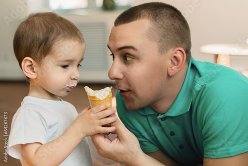 Маленький мальчик в компании папы кушает мороженое