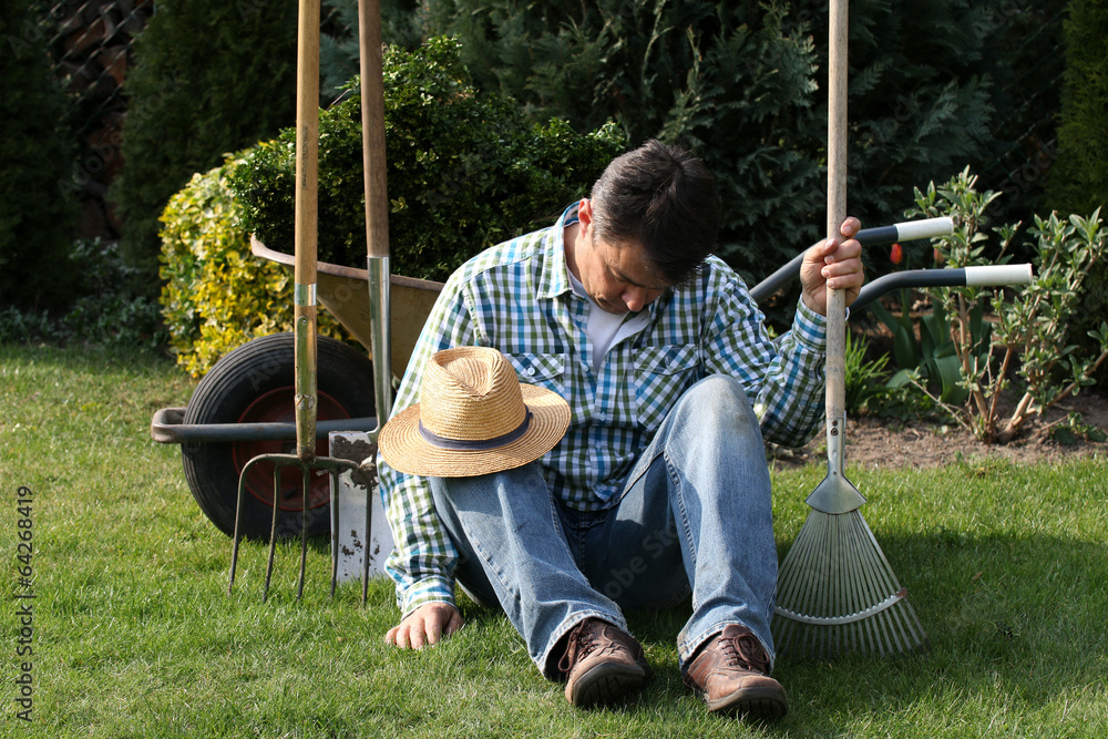 Gärtner beim Pause machen, schläft, hält Rechen StockFoto Adobe Stock